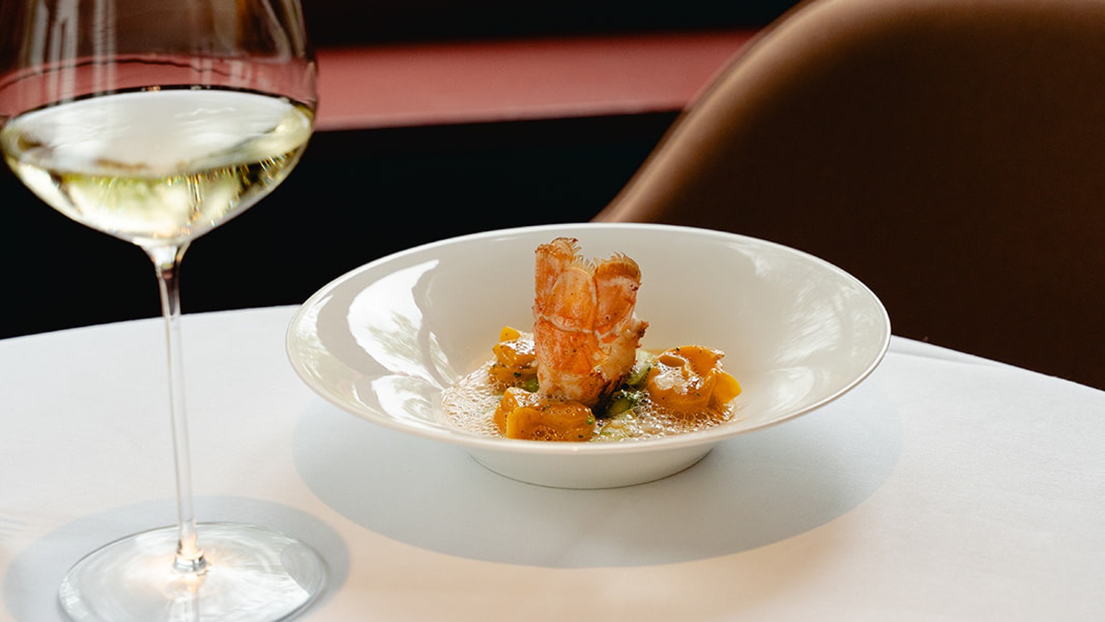 Lobster dish and a glass of wine on a laid table at Brabohoeve